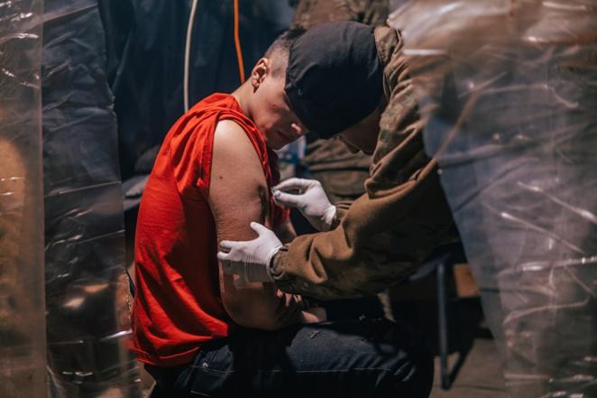 Un combatiente pone una inyección a un herido en la acería. 