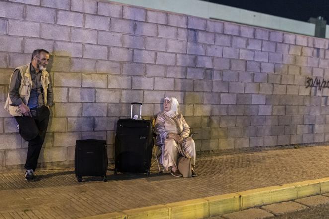 Dos personas esperan con su equipaje en la frontera de España y Marruecos en Melilla. 