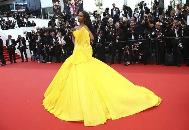 Jasmine Tookes - Alfombra roja del segundo día del Festival de Cannes. Muy colorida con un voluminoso diseño amarillo con volantes de Tony Ward Couture que incluía un gran aplique en el costado derecho como si se tratase de un abanico.