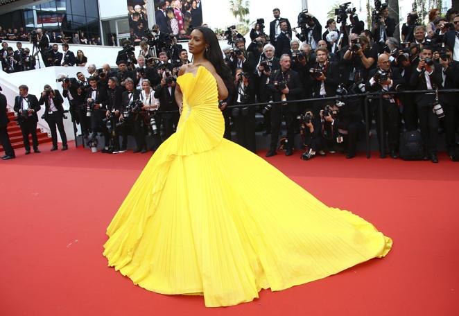 Jasmine Tookes - Alfombra roja del segundo día del Festival de Cannes. Muy colorida con un voluminoso diseño amarillo con volantes de Tony Ward Couture que incluía un gran aplique en el costado derecho como si se tratase de un abanico.
