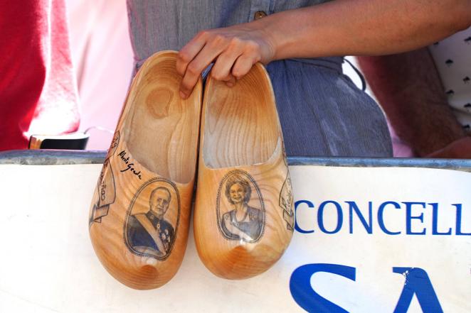 Un hombre sostiene unos zapatos de madera con la imagen de los monarcas a la llegada del Rey emérito a la 3ª Regata del IV Circuito Copa de España 2022. 