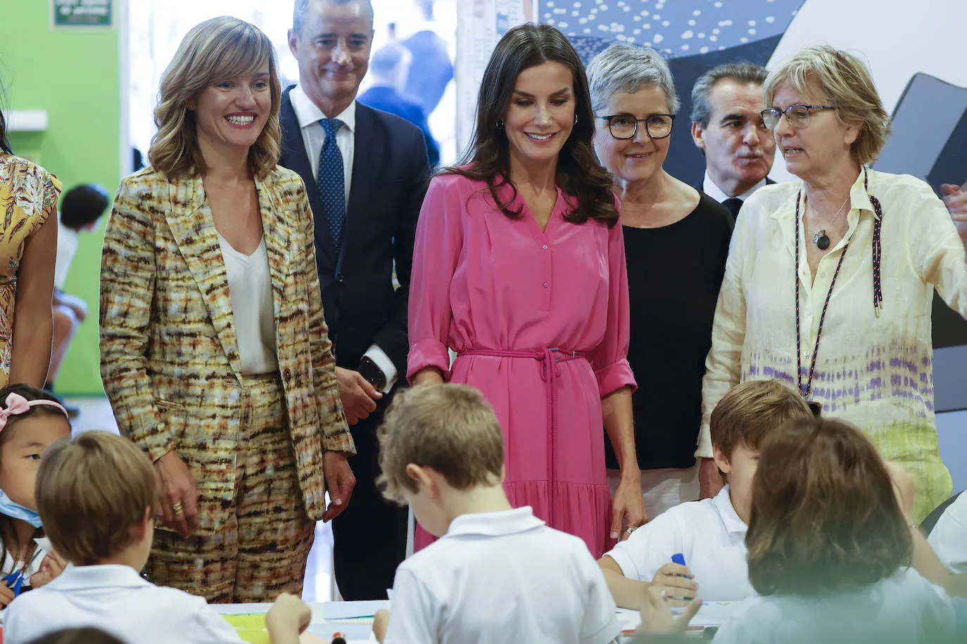 La reina Letizia (c), acompañada por la ministra de Educación y Formación Profesional, Pilar Alegría (i), y la directora de la Feria del Libro de Madrid, Eva Orúe (2d), en un taller impartido para niños