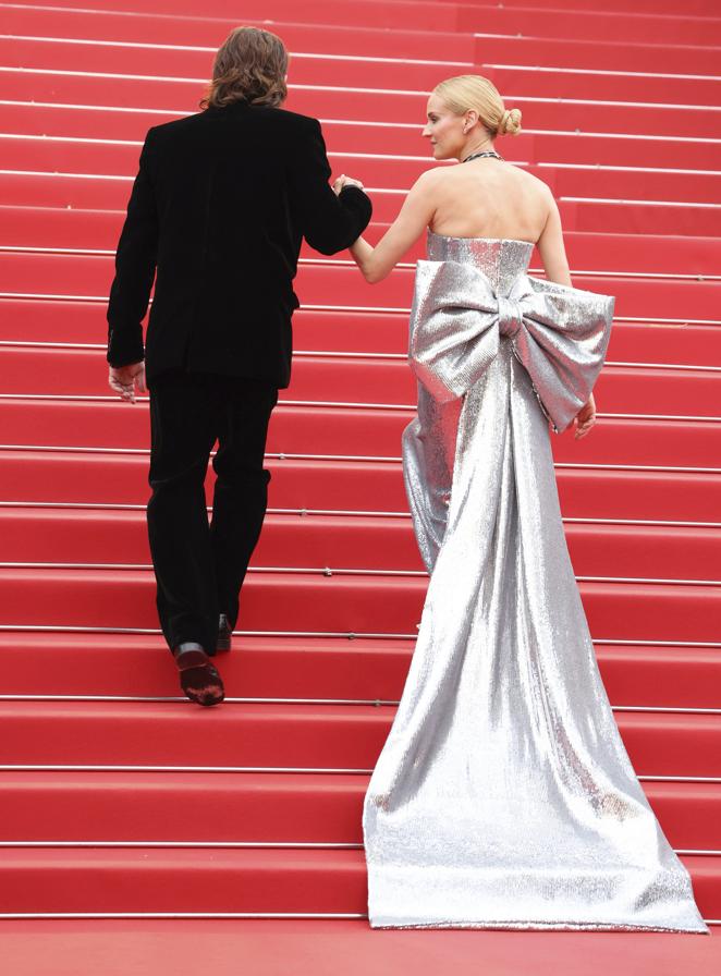 Diane Kruger y Norman Reedus en el Festival de Cannes 2022. Se trata de un diseño de escote palabra de honor y un corte midi con un llamativo lazo en la parte trasesa, de la firma AMI.