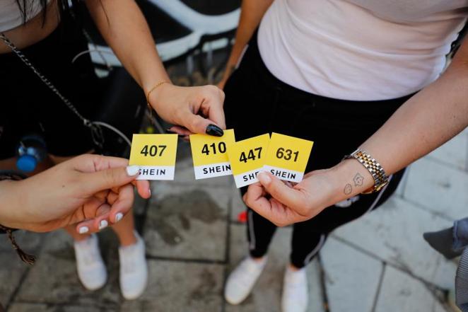 Las personas en espera se cuentan por cientos. En la imagen, unas chicas muestran sus números