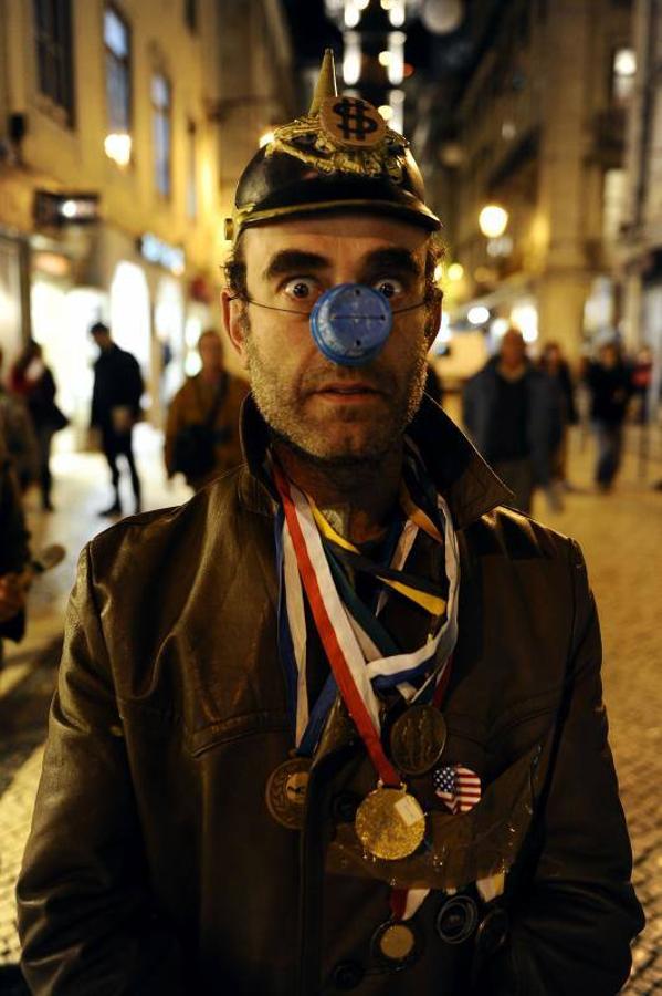 17 de noviembre de 2009. Un manifestante anti-OTAN disfrazado de payaso mira fijamente a la cámara durante una protesta en Lisboa. Los días 19 y 20 de noviembre de 2010 se celebró en la capital de Portugal una Cumbre de Jefes de Estado y de Gobierno de la OTAN.. 