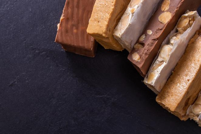 Turrón de chocolate. Este turrón tiene 525 Kcal por cada 100 gramos del producto. Además de aportar 31 gramos de grasas (de las que 15 son saturadas), contiene 51 gramos de hidratos de carbono, de los que 40,1 son azúcares.