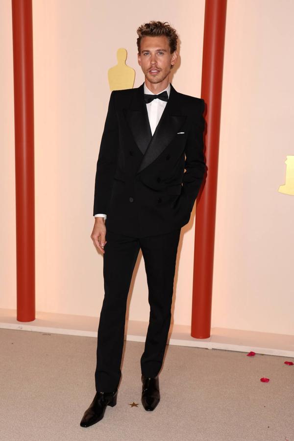 Austin Butler. El actor, nominado por su papel de Elvis, ha lucido esmoquin cruzado con hombreras XXL y botines de charol de Saint Laurent. Lo ha acompañado de joyas de Cartier.