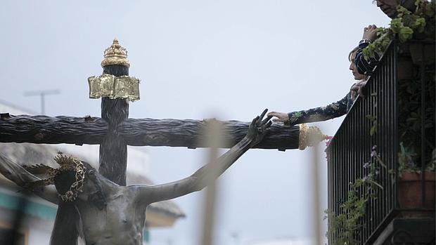 Una mujer acaricia los dedos del Cristo de Gracia un Jueves Santo