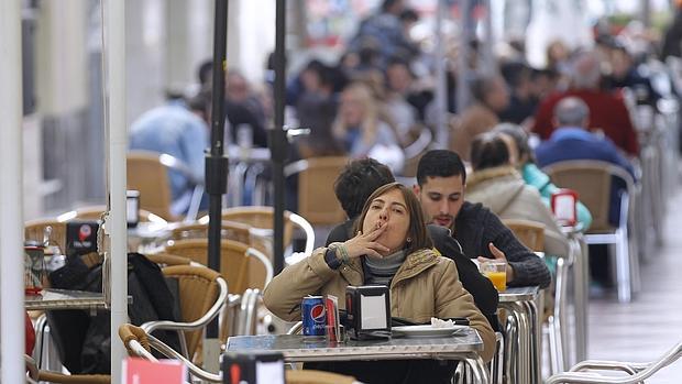 Una mujer fuma un cigarrillo en una terraza de la calle de la Plata