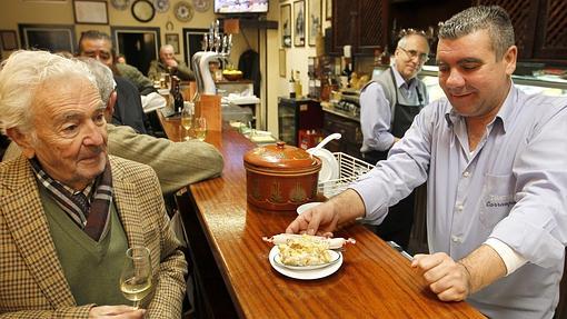 Un trabajador de Bar Carrasquín sirviendo ensaladilla a sus clientes