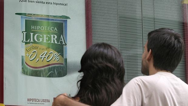 Una pareja contempla publicidad bancaria sobre hipotecas