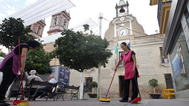 Dos mujeres barren ante la entrada del Ayuntamiento de Fuente Palmera