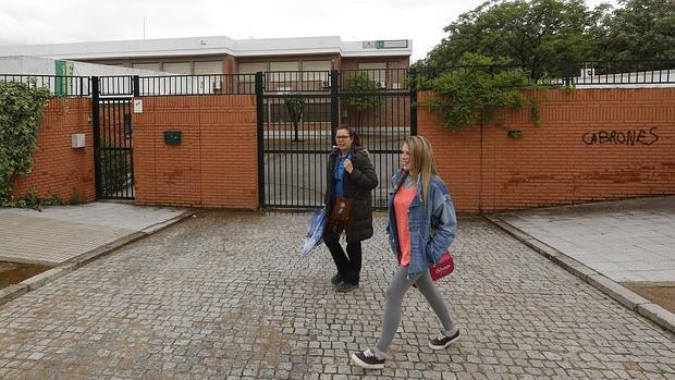 Dos personas pasan frente a la fachada del colegio Juan de Mena