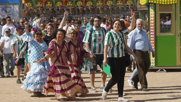 Varios aficionados se dirigen al estadio con camisetas y trajes de flamenca