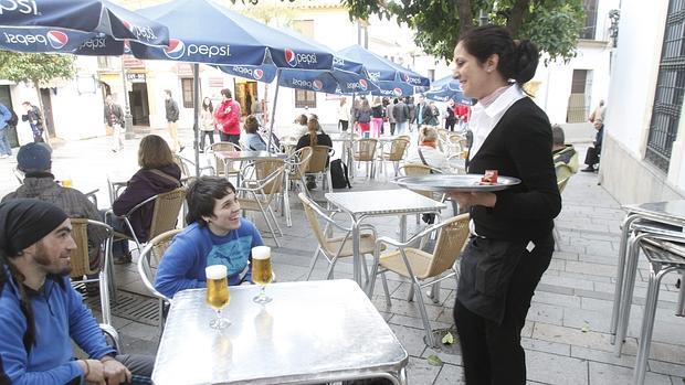 Una camarera atiende a dos personas en un bar de Córdoba