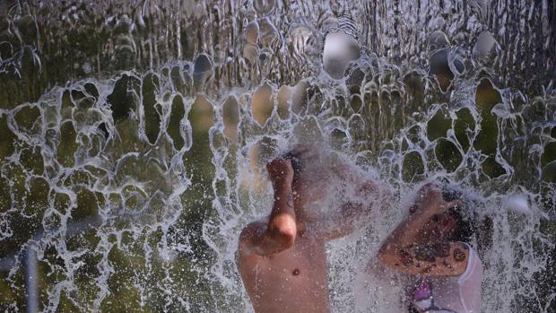 Dos chicos se mojan en una de las fuentes del Vial de Córdoba