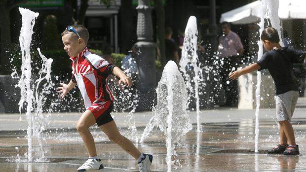 Dos niños se refrescan en los chorros de Las Tendillas