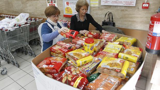 Dos voluntarias de Banco de Alimentos junto a un contenedor de colecta