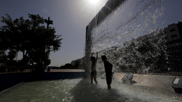 Unos niños sofocan el calor entre juegos y risas en una de las fuentes del Vial