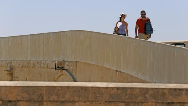 Turistas atraviesan el Puente Romano bajo el rigor de la canícula cordobesa