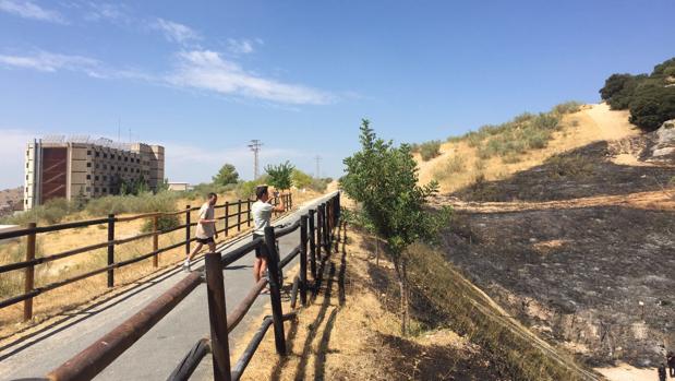 Dos jóvenes toman fotos del rastro del incendio, con el hospital Infanta Margarita al fondo