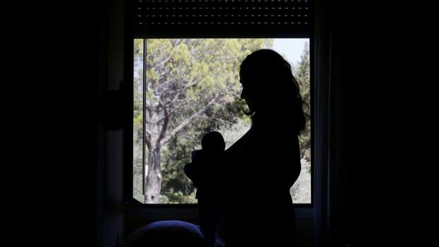 Una joven sostiene a su bebé junto a la ventana en la residencia de Fuente de Vida