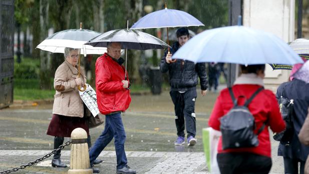 Varias personas con paraguas ante el parque de Colón