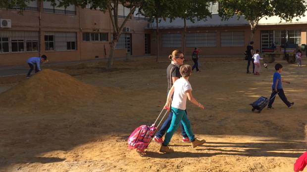 Padres y alumnos del colegio Europa este lunes por el patio con la apisonadora al fondo