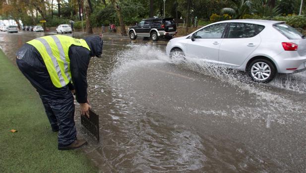 Un operario levanta una alcantarilla en una calle del centro de Málaga por las fuertes lluvias