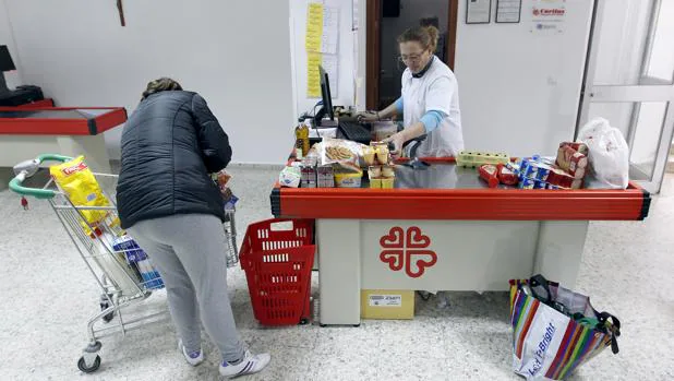 Una mujer realiza su compra en el economato de Cáritas de la capital