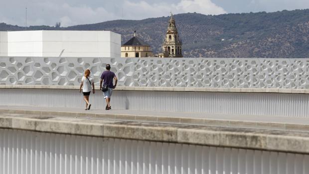 Dos personas pasean sobre el puente del Arenal, frente al C3A