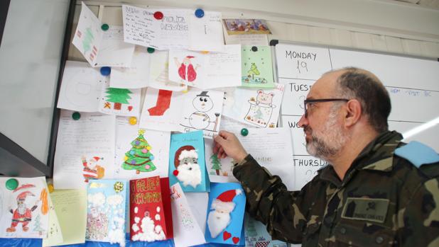 Un soldado observa una de las felicitaciones en el mural en el que las han colocado