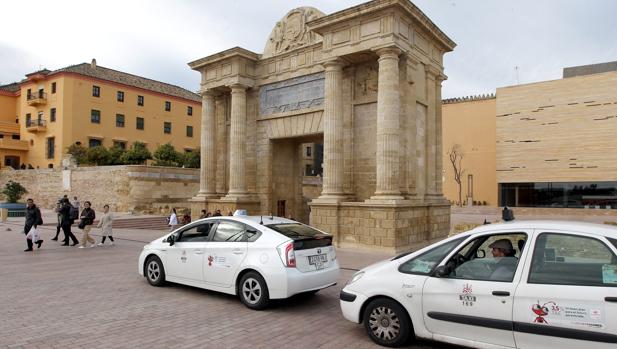 Dos taxis pasan delante de la Puerta del Puente