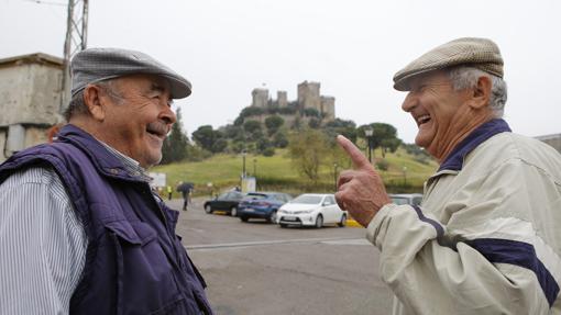 Dos hombres conversan frente al castillo de Almodóvar