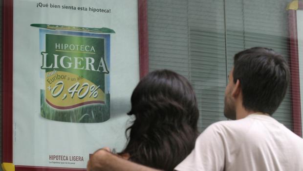 Una pareja mira una publicidad sobre hipotecas en un banco