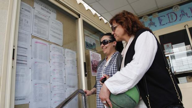 Dos madres consultan un tablón de anuncios en un centro educativo