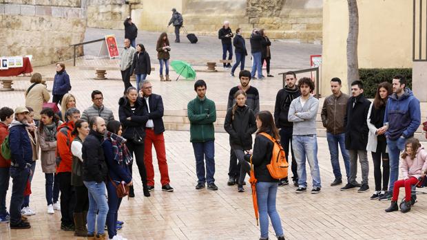 Una profesional realiza indicaciones a un grupo de visitantes junto a la Puerta del Puente