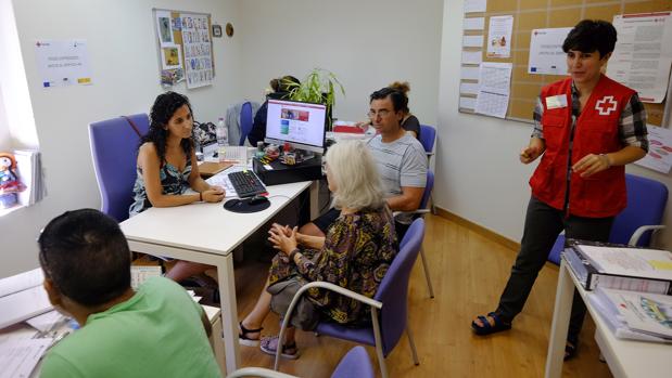 Una trabajadora de Cruz Roja atiende a una familia desempleada en Sevilla