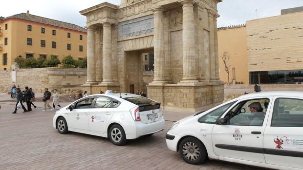 Dos taxis pasan delante de la Puerta del Puente Romano de Córdoba, acceso de las cofradías