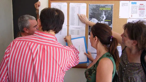 Un grupo de padres consultan unas listas de escolarización en un colegio