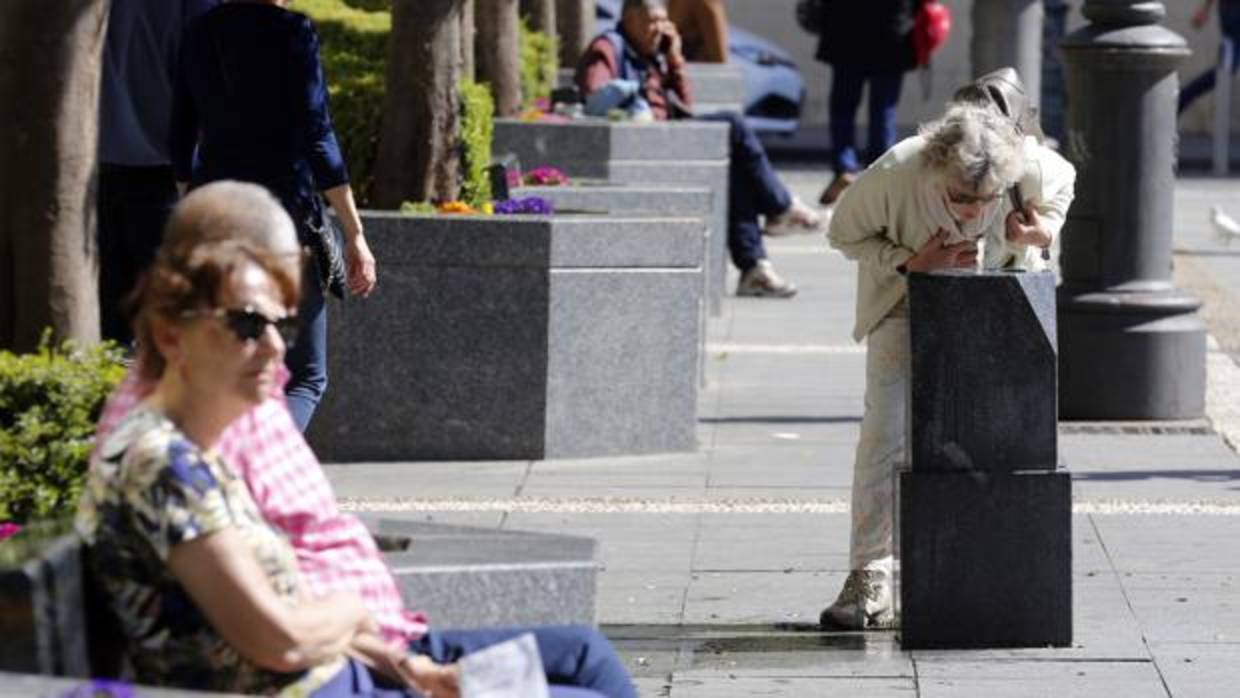 Una mujer se refresca en una fuente de las Tendillas