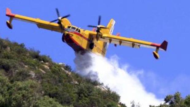 Un avión descarga agua sobre el monte bajo