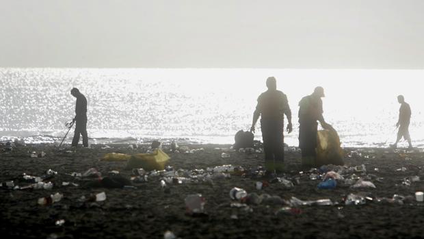 Operarios de limpieza en la playa tras una noche de San Juan