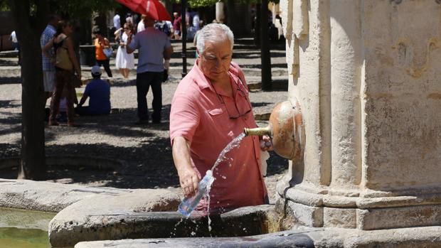 Un hombre rellena su botella con agua en el Patio de los Naranjos