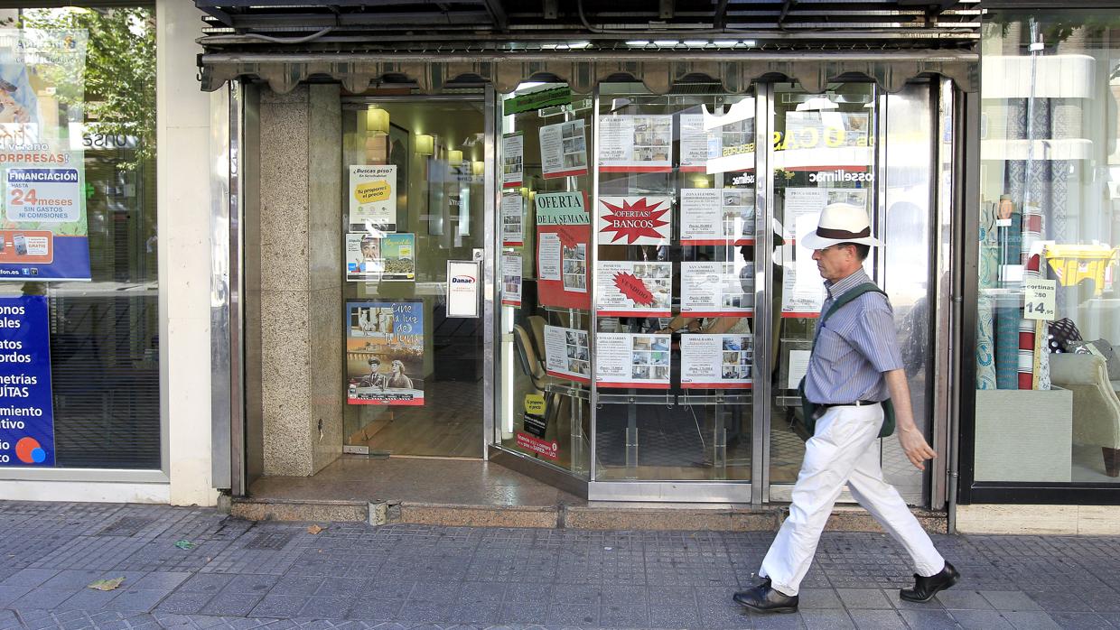 Un viandante camina delante del escaparate de una inmobiliaria