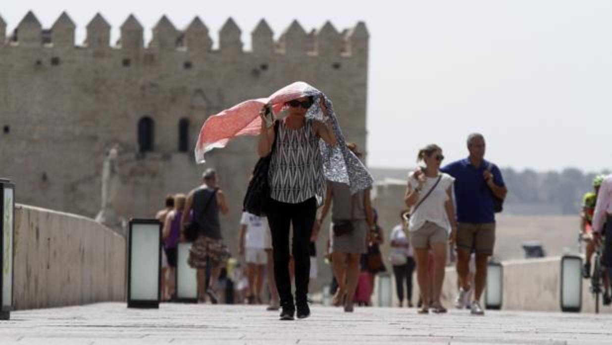 Una turista se cubre el rostro este sábado al atravesar el Puente Romano de Córdoba