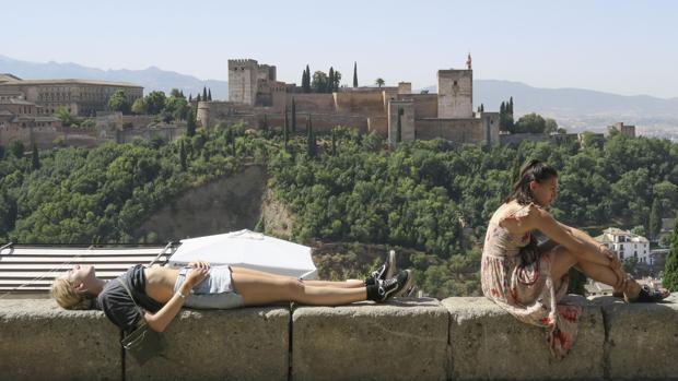 Dos turistas toman en sol en Granada aprovechando las altas temperaturas