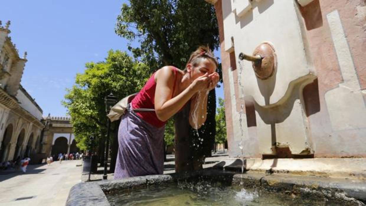 Una turista se refresca en una fuente del Patio de los Naranjos