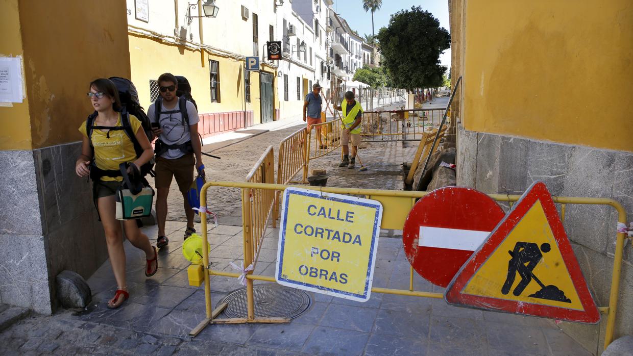Turistas pasean junto la calle Caballerizas Reales, cortada por obras