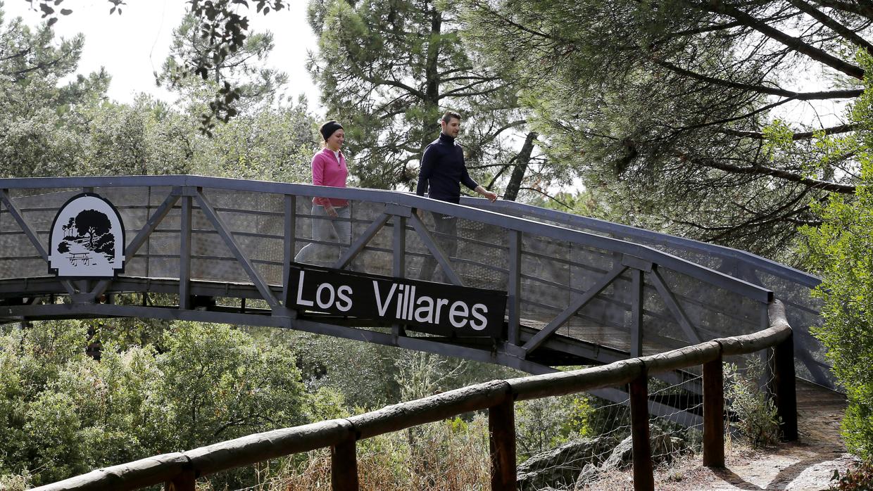 Dos personas pasean sobre un puente en el parque periurbano de Los Villares